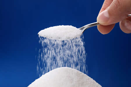 Heap of sugar and pouring more from a spoonの写真素材
