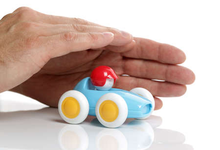Toy car protected by human hands on white backgroundの写真素材