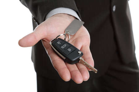 Car salesman or rental man giving over a car keyの写真素材