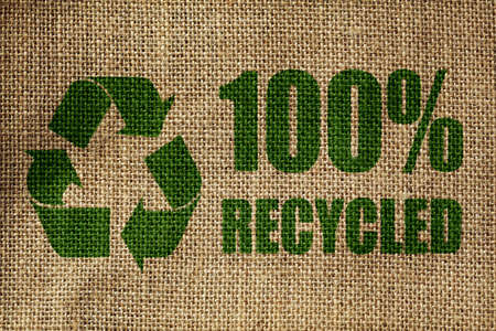 Recycling symbol and one hundred per cent recycled sign on the side of a hessian bag in greenの写真素材