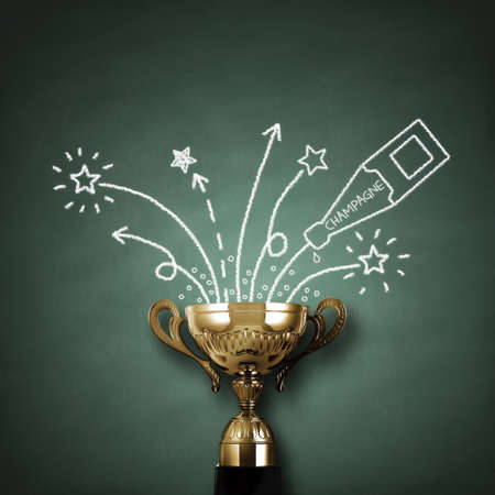 First place championship trophy or cup in front of blackboard with champagne and fireworks concept for winning and successの写真素材