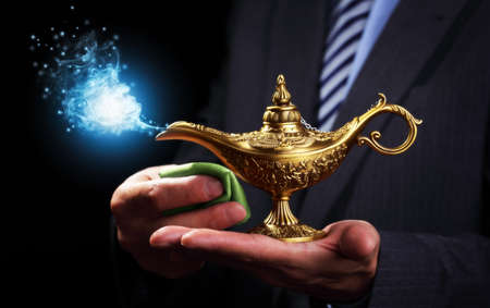 Businessman holding and rubbing a magic Aladdins genie lamp concept for business aspirations, hope and wishesの写真素材