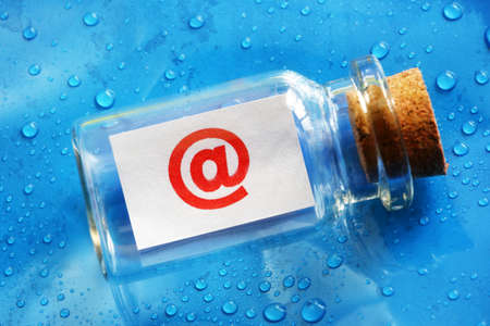 E-mail address @ symbol message in a bottle concept for contact us, assistance and business supportの写真素材