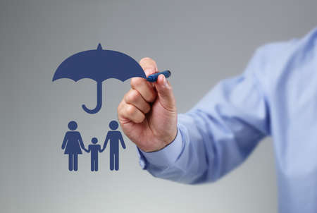 Businessman hand drawing an umbrella above a family concept for protection, security, finance and insuranceの写真素材