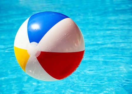 Beach ball floating in swimming pool abstract concept for summer vacations, relaxation and fun in the sunshineの写真素材