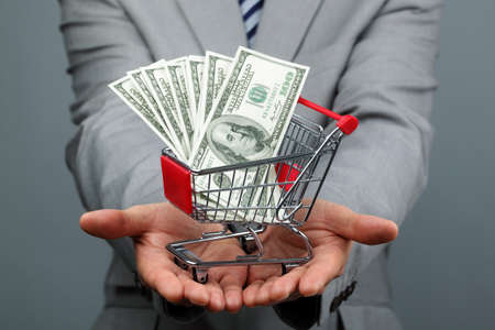 Businessman with shopping trolley full of moneyの写真素材