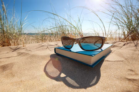 Book and sunglasses on the beach for summer reading and relaxingの写真素材