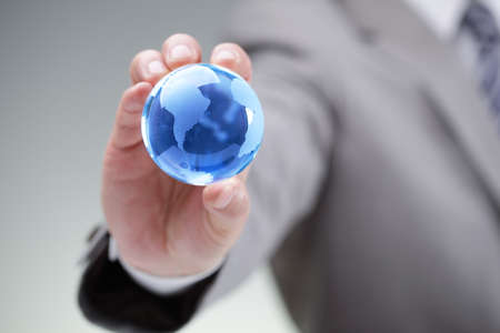 Business man holding a blue globe in his hand symbol for global business, communications or environmental conservationの写真素材