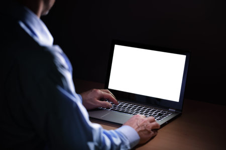 Late night internet addiction or working late man using laptop at a desk in the dark