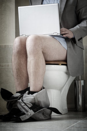 Businessman working on laptop while sitting on toilet concepts for urgent deadline, working from...