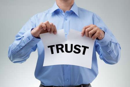 Businessman tearing up sign saying trust concept for infidelity, dishonesty and cheatingの写真素材