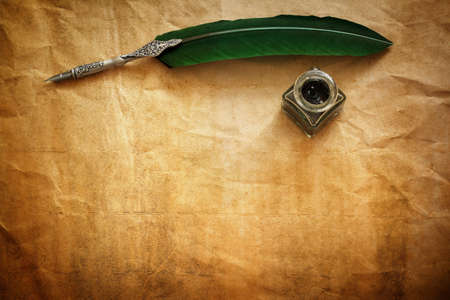 Quill pen and ink well resting on blank parchment paper with copy space for messageの写真素材