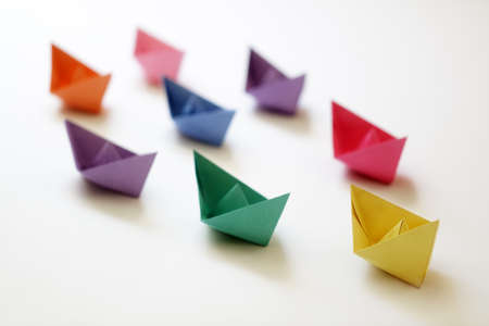 Paper boats of multi-colour following a leader boat concept for leadership, teamwork and winning successの写真素材