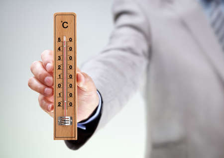 Businessman holding thermometer measuring high temperature concept for climate, stress, under pressure or deadlineの写真素材