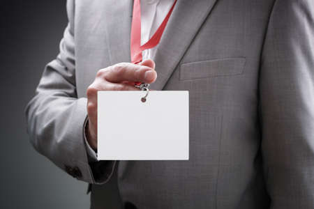 Businessman at an exhibition or conference showing a blank security identity name card on a lanyardの写真素材