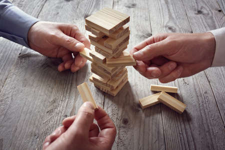 Planning, risk and team strategy in business, businessman gambling placing wooden block on a towerの写真素材