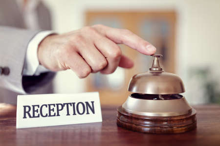 Businessman ringing a hotel reception service bell to attract attentionの写真素材