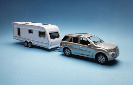 Toy car towing a caravan of generic design on blue backgroundの写真素材