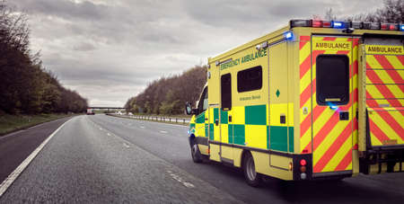 British ambulance responding to an emergency in hazardous bad weather driving conditions on a UK motorwayの写真素材