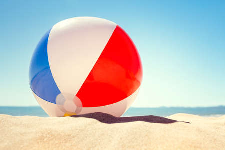 Beach ball resting in sand dune concept for childhood summer vacations, family holiday and healthy lifestyleの写真素材