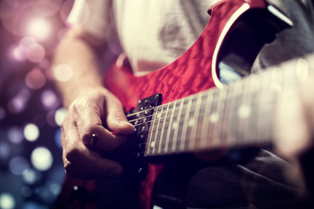 A rock lead guitarist playing electric guitar in action on stage