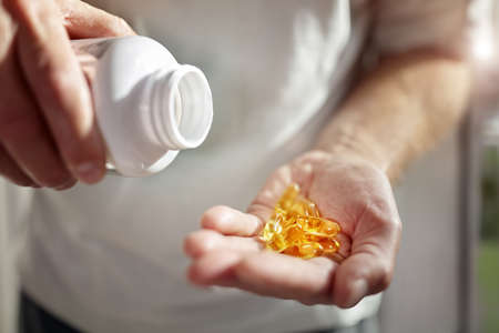 Bottle of omega 3 fish oil capsules pouring into handの写真素材