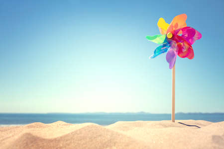 Summer beach background, pinwheel or windmill in the sand concept for vacation copy or messageの写真素材