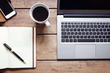Open laptop with notepad and smartphone workspace on desk from aboveの写真素材