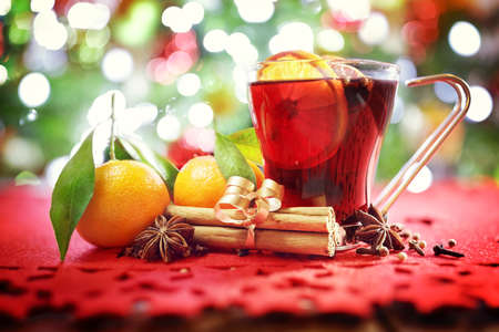 Christmas background with hot mulled wine, oranges, cinnamon sticks in front of treeの写真素材