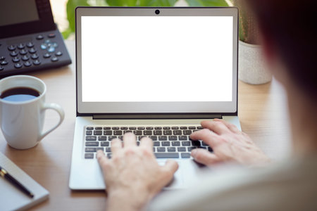 Man with laptop computer on desk working in office with blank screen