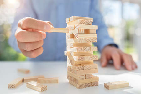 Planning, risk and strategy in business, businessman gambling placing wooden block on a towerの写真素材