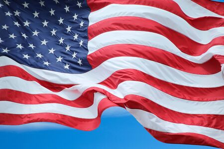 Amercian flag fluttering under blue sky.の写真素材