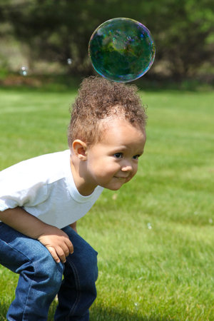 Heavy bubble, 2-year-old boy plays with bubbles at backyard.