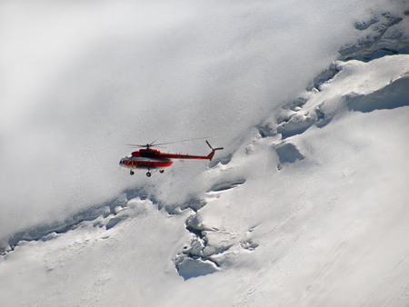 Helicopter flying in the background of snowy mountainsの写真素材