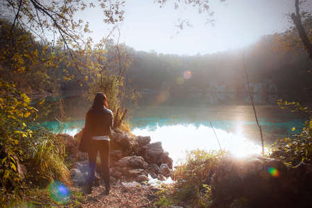 lady at the lake in autumn season, young dark woman looking at the landscape in autumnの写真素材