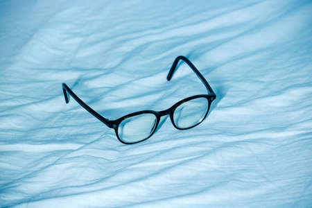 eye glasses on blue waves, the object is on a waved velvetの写真素材