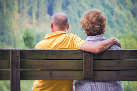 middle aged male and female sitting on bench, engaged people looking at nature view