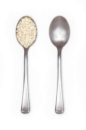 food inequality, two spoons: one full of rice and the other with just a grainの写真素材