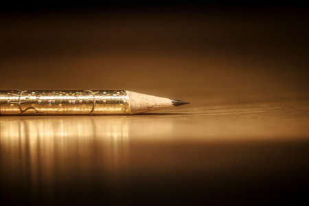 single golden pencil on dark background, writing and drawing with copy spaceの写真素材