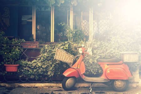 italian scooter, traditional style motorcycle with foliage (image with bright light effect)の写真素材