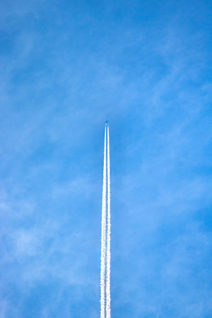 airplane flies leaving in the sky, bottom view of jet on blue background