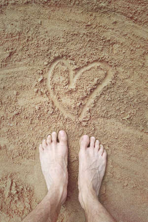 feet on the sand with heart, love for walking on the beach barefootの写真素材