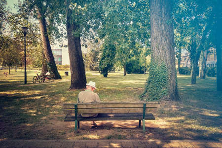 back view of senior on a bench, lonely old man in a parkの写真素材