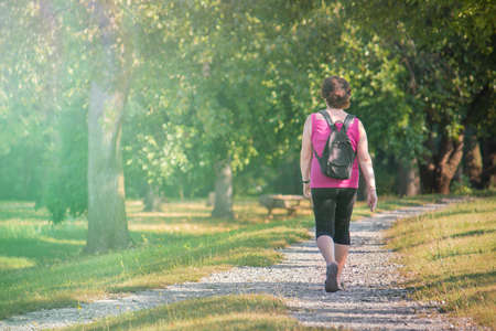 Middle age woman walking in a park, outdoor quiet stroll (image with copy space)の写真素材