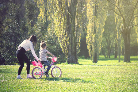 little girl having fun with bike. Learning to ride a bicycle at the parkの写真素材