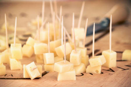 tasting of italian cheese, cubes of appetizer on wooden cutting boardの写真素材