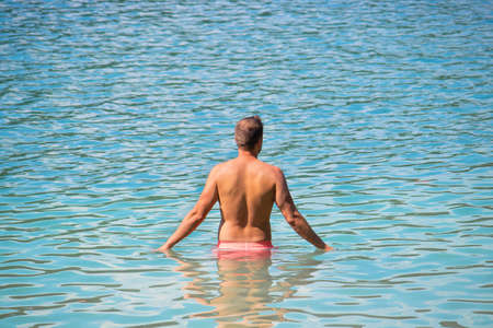 man relaxing in the water in a summer day, attractive caucasian male wearing swimsuit enjoying the seaの写真素材