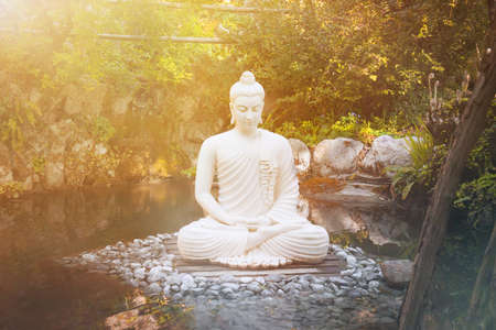 buddha consciousness light. Buddha statue meditating in the nature near the waterの写真素材