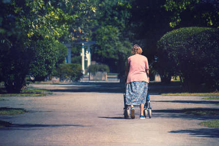 Senior woman with walker outdoors, handicapped lady with a walking disabilityの写真素材