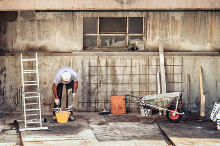 bricklayer working in a construction site, man using trowel and a spatula to spread mortarの写真素材